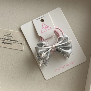 Close-up of silver bow hair tie with white pearls and pink elastic on display card
