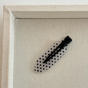 Detailed macro view of a translucent hair clip with chic black polka dots on canvas