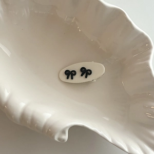 Gros plan d'une barrette ovale blanc crème avec deux nœuds noirs élégants sur un plateau