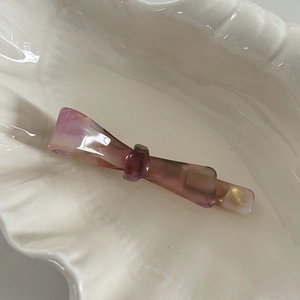 Close-up of elegant purple marble acetate bow hair clip resting in shell tray
