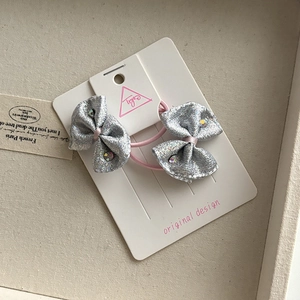Detail view of silver sequin bow hair ties with colorful rhinestones on a display card