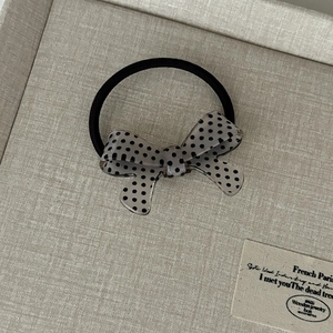 Close-up of black elastic hair tie with a grey translucent polka dot bow detail