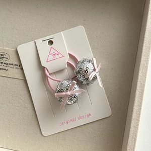Close-up of pink elastic hair ties with silver sequin balls and silk bow details