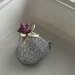 Detail of silver sequin hair clip with purple star and gold-edged white bow