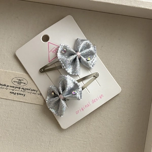 Close-up of silver glitter bow hair clips with rhinestones on a display card