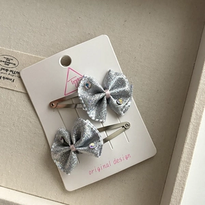 Close-up of silver glitter bow hair clips set with pink ribbon and colorful rhinestones