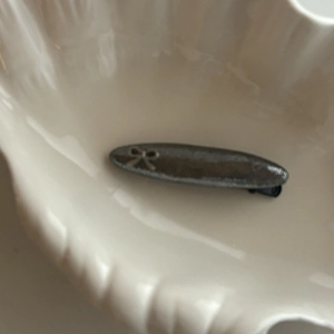 Vue détaillée d'une pince à cheveux en métal gris foncé avec nœud argenté sur céramique