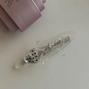 Détail d'une pince à cheveux en acétate avec dentelle, cœur à pois et nœud élégant