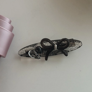 Détail d'une pince à cheveux en acétate avec dentelle noire et nœud tridimensionnel