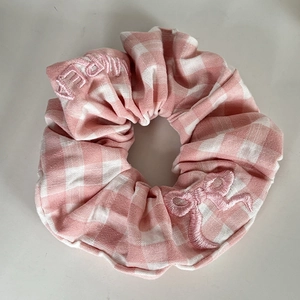 Detailed view of pink and white gingham scrunchie with bow and letter embroidery