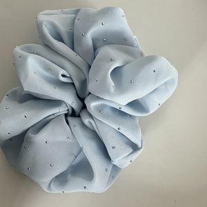 Detailed close-up of light blue fabric hair scrunchie with sparkling silver rhinestones