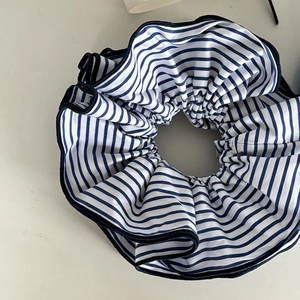 Détail d'un chouchou en tissu à rayures bleues et blanches avec bords volantés et couture bleue