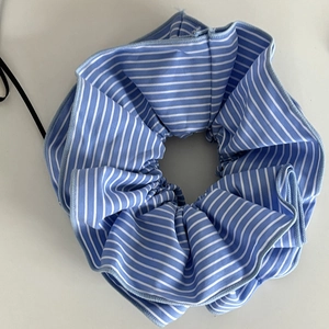 Chouchou en tissu à rayures bleues et blanches avec design plissé sur fond blanc