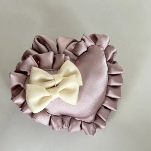 Macro detail of dusty pink satin scrunchie with layered lace edge and beige fabric bows