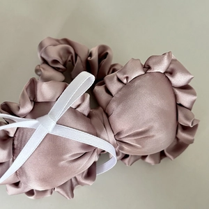 Close-up of pink satin ruffled hair scrunchies with white ribbon bow details