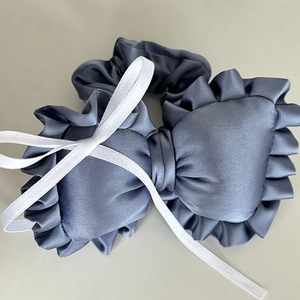 Close-up of blue-grey satin bow scrunchies set with elegant ruffled fabric details