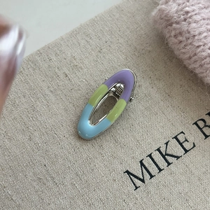 Detailed macro shot of an oval enamel hair clip with pastel purple green and blue colors
