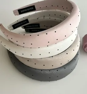 Close-up of padded polka dot headbands in pink, white, and gold with soft satin texture