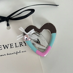 Eleganter herzförmiger hohler Haarclip mit Strass und Schleife auf Schmuckkarte