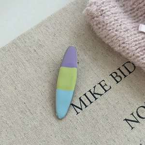 Detail of a tri-color cream enamel hair clip with a minimalist silver metal edge