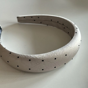 Detail of padded champagne satin headband featuring black polka dots and interior label