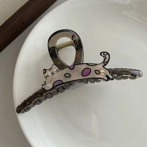 Gros plan d'une pince à cheveux chat en acrylique gris fumé et blanc nacré brillant