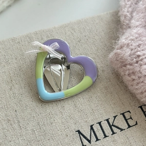 Detail of heart hair clip with colorful enamel finish and white lace bow decoration