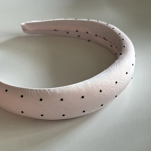 Close-up of pink padded headband with black polka dot beads and smooth satin texture