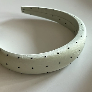 Detailed texture of mint green padded polka dot headband with black stud embellishments