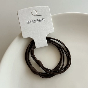 Détail de l'élastique à cheveux marron foncé multi-brins sur un plateau en céramique