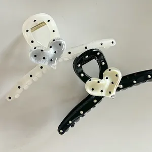 Détail de pinces à cheveux à pois noir et crème avec un petit cœur tridimensionnel