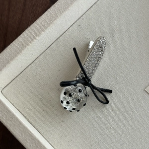 Détail de la pince à cheveux avec strass brillants, nœud noir et perle à pois