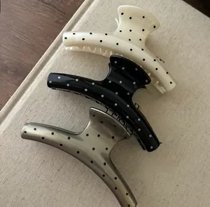 Three acetate hair claws with retro polka dot patterns displayed on vintage books