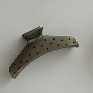 Detailed top view of a large gunmetal hair claw clip with black polka dots on light gray background