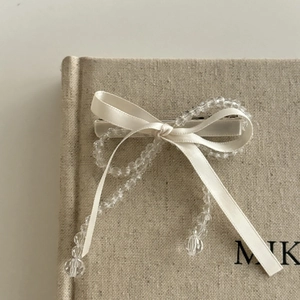 Barrette à cheveux nœud en ruban crème avec perles sur un fond de livre élégant
