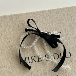 Détail d'une pince à cheveux à nœud en satin noir avec perles transparentes décoratives