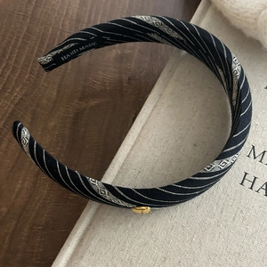 Detail of handmade striped fabric headband with geometric patterns and gold metal button
