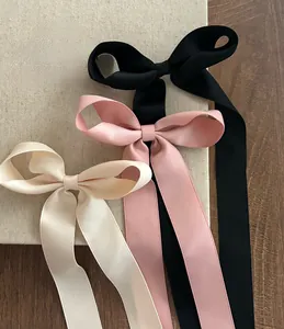 Vue détaillée de barrettes à nœud en satin avec longs rubans en noir, rose et blanc crème