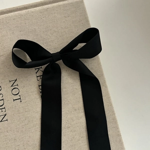 Barrette à cheveux élégante avec nœud en soie noire et longs rubans sur fond texturé