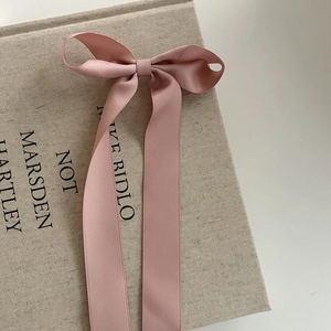 Détail d'une pince à cheveux à nœud en satin rose avec de longs rubans fluides