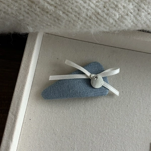 Vue détaillée d'une pince à cheveux en denim bleu clair avec nœud et pendentif argent