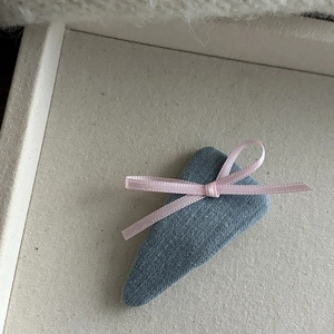 Gros plan d'une pince BB en denim avec un nœud en ruban rose sur plateau en toile