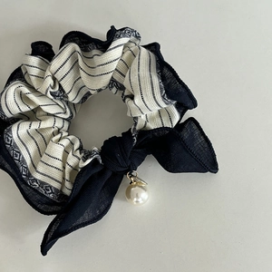 Detail of striped fabric scrunchie with sheer black ribbon bow and white pearl pendant