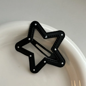 Barrette en forme d'étoile noire à pois blancs sur un plateau en céramique blanche