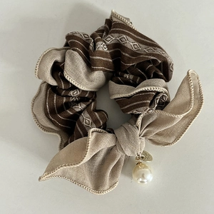 Detail of coffee striped hair scrunchie with chic faux pearl and gold metal charm