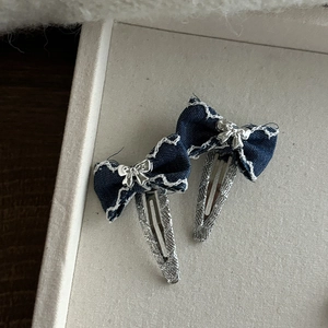 Détails des barrettes en denim bleu foncé avec coutures blanches et nœud argenté