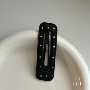 Gros plan sur la barrette rectangulaire noire mate à pois blancs sur plateau céramique