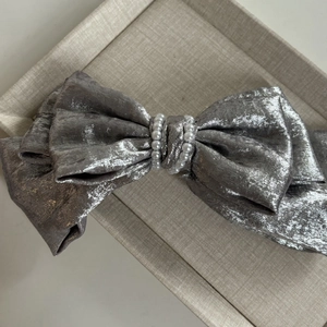 Détail d'un nœud papillon argenté pour cheveux avec des perles blanches de luxe