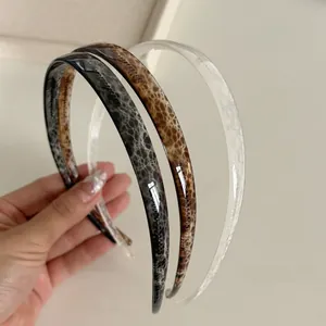 Close-up of three non-slip plastic headbands in marble, leopard, and clear brown textures