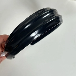 Détail d'un serre-tête large en cuir PU noir avec un design plissé élégant